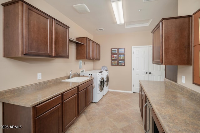 clothes washing area featuring visible vents, baseboards, a sink, cabinet space, and washing machine and dryer