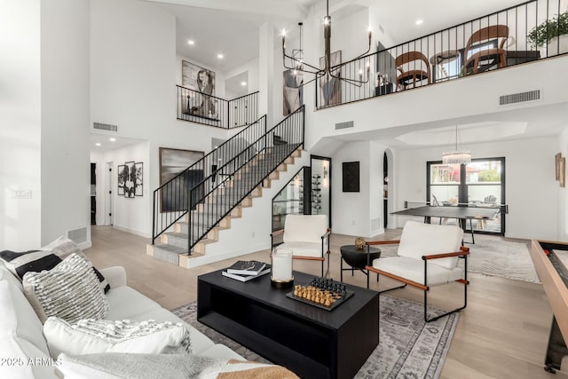 living area with an inviting chandelier, wood finished floors, and visible vents