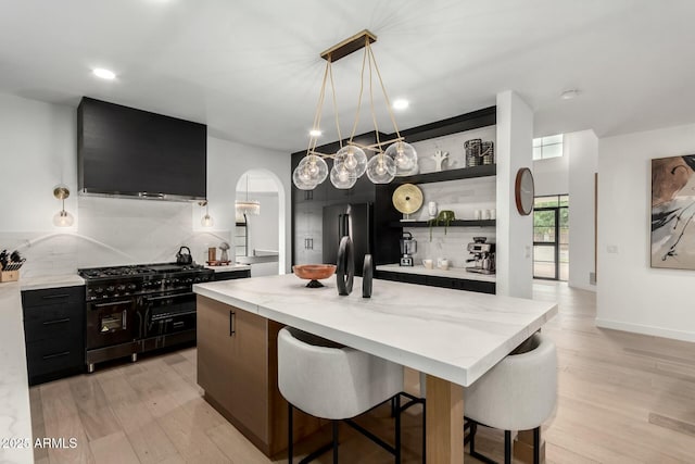 kitchen with open shelves, light wood-type flooring, arched walkways, and black appliances