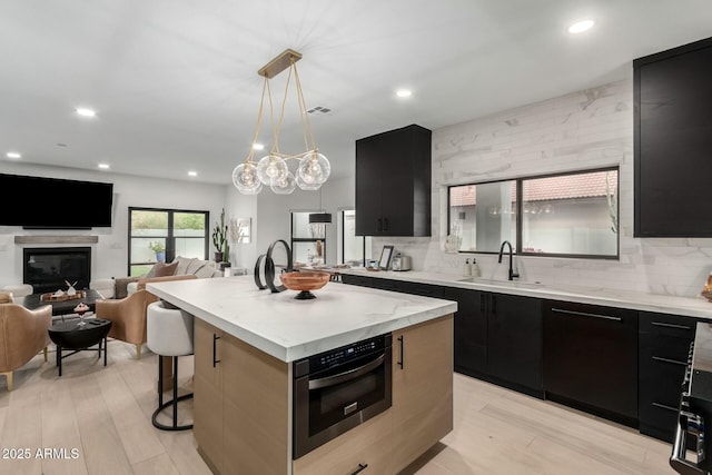 kitchen featuring a sink, backsplash, wall oven, modern cabinets, and dark cabinets