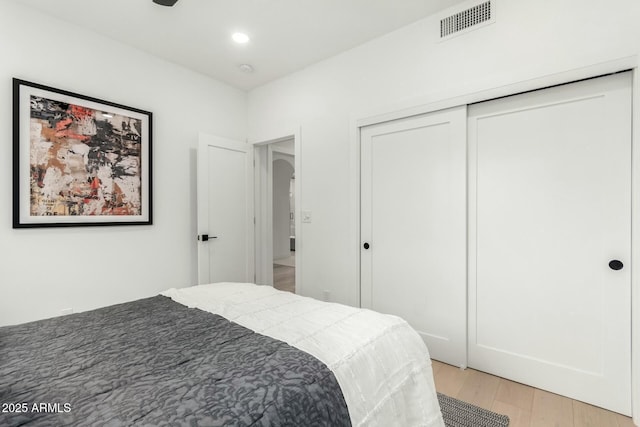 bedroom with recessed lighting, light wood-style floors, visible vents, and a closet