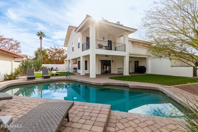 rear view of house featuring stucco siding, fence, a patio area, a balcony, and a tiled roof