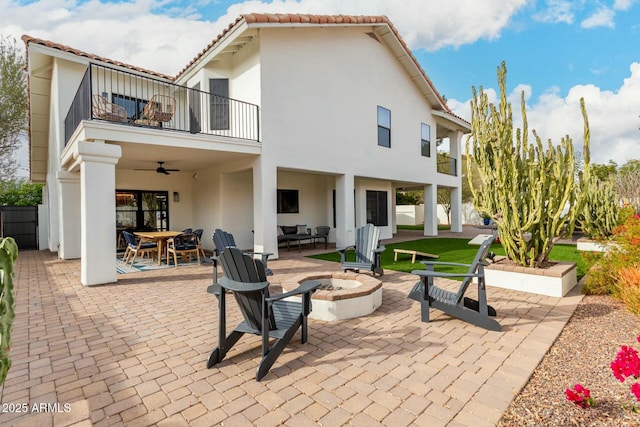 back of house with a fire pit, a tiled roof, stucco siding, a balcony, and outdoor dining space