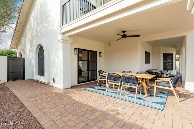 view of patio with a balcony, outdoor dining area, and a ceiling fan