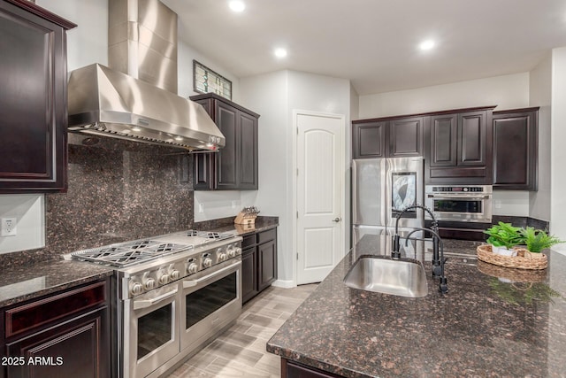 6251 E Bramble Berry Ln, Cave Creek, AZ 85331 - kitchen featuring stainless steel appliances, wall chimney exhaust hood, tasteful backsplash, dark stone countertops, and dark brown cabinets