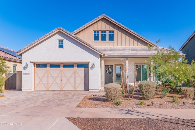 view of front of property featuring a tiled roof, decorative driveway, board and batten siding, and stucco siding