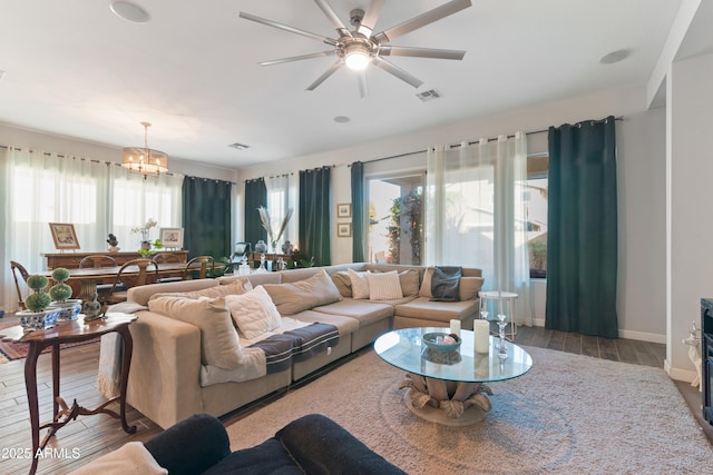 living room featuring hardwood / wood-style flooring, ceiling fan with notable chandelier, and a healthy amount of sunlight