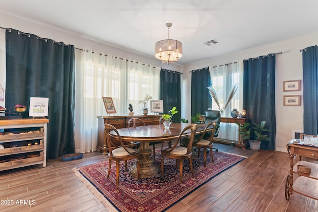 dining space featuring an inviting chandelier, baseboards, visible vents, and wood finished floors