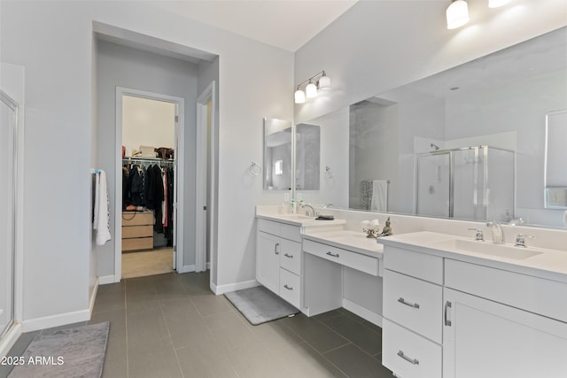 bathroom featuring double vanity, a stall shower, a spacious closet, and a sink