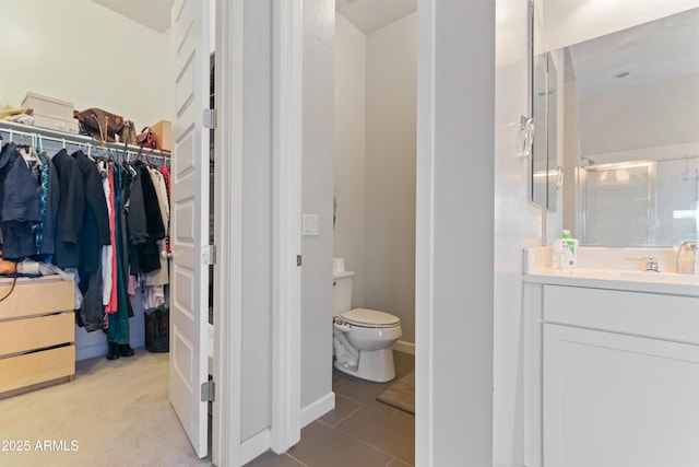 full bathroom with a spacious closet, toilet, a stall shower, vanity, and tile patterned flooring