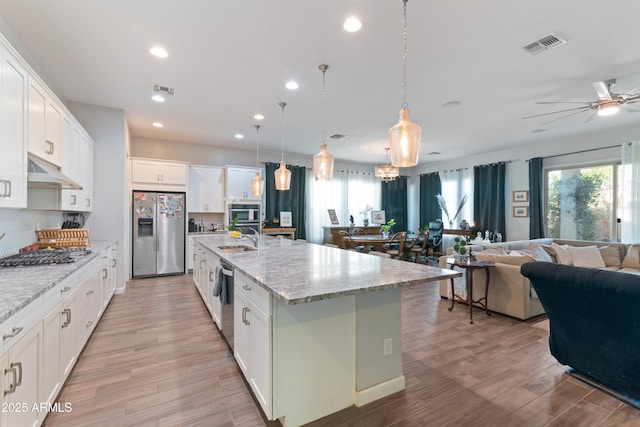 kitchen featuring white cabinetry, hanging light fixtures, stainless steel appliances, and a large island with sink