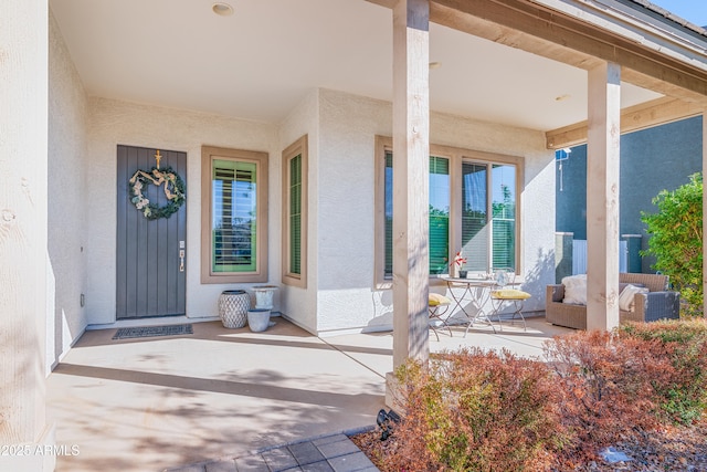 doorway to property with a porch and stucco siding