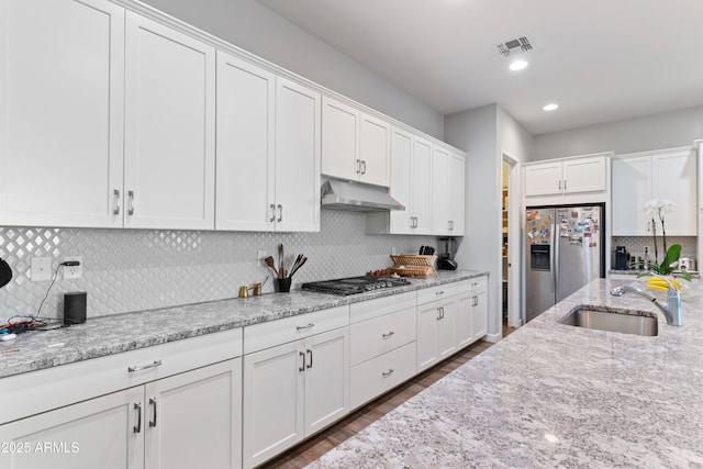 kitchen with visible vents, appliances with stainless steel finishes, under cabinet range hood, white cabinetry, and a sink