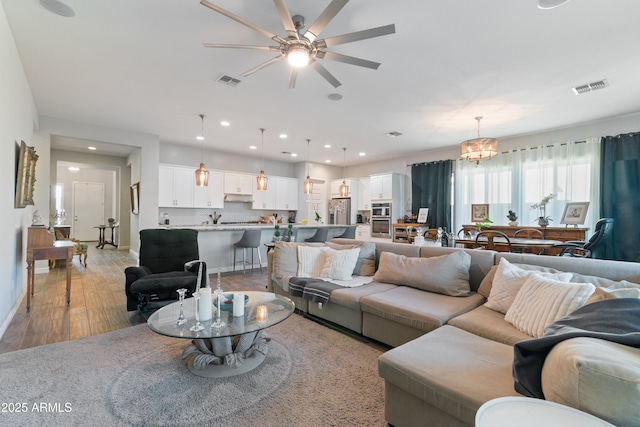 living room featuring baseboards, light wood-type flooring, visible vents, and recessed lighting