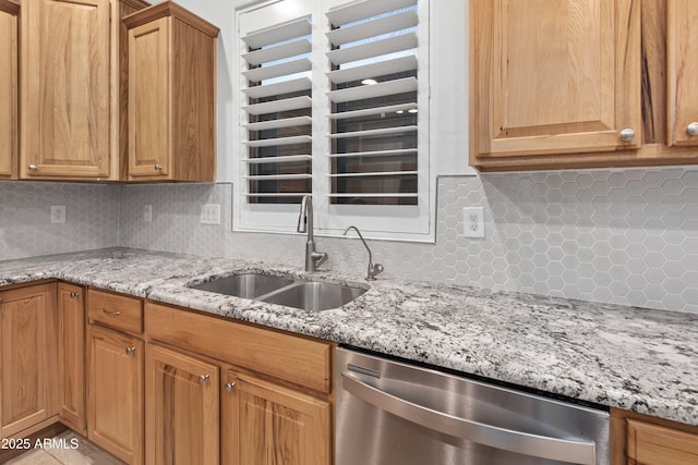 kitchen featuring tasteful backsplash, light stone countertops, sink, and stainless steel dishwasher