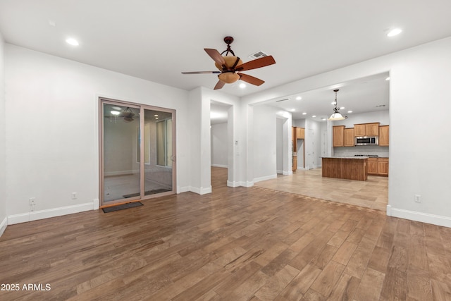 unfurnished living room with ceiling fan and light wood-type flooring