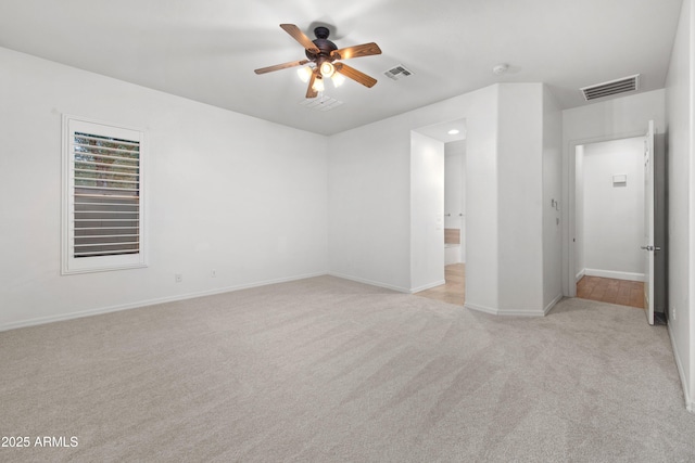 unfurnished bedroom with ensuite bathroom, light colored carpet, and ceiling fan