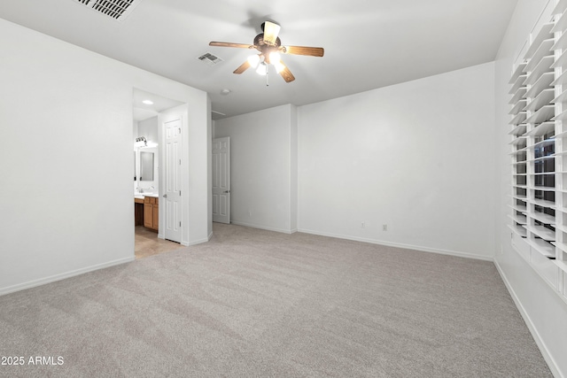 unfurnished bedroom featuring ceiling fan, light colored carpet, and ensuite bath