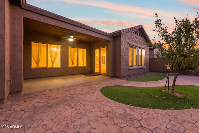 back house at dusk with a yard and a patio area