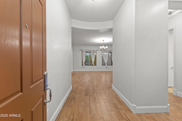 hall featuring an inviting chandelier and light hardwood / wood-style flooring