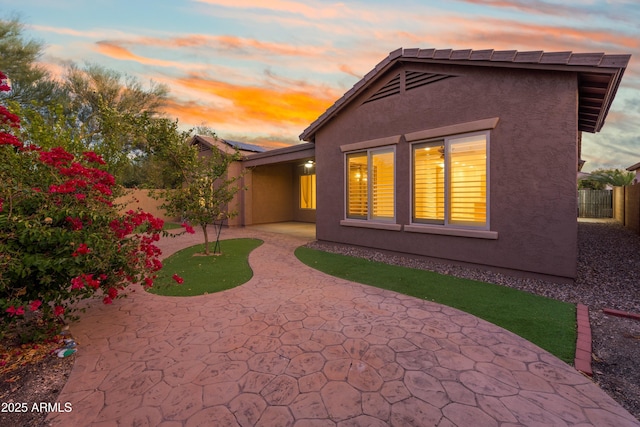 back house at dusk featuring a patio area