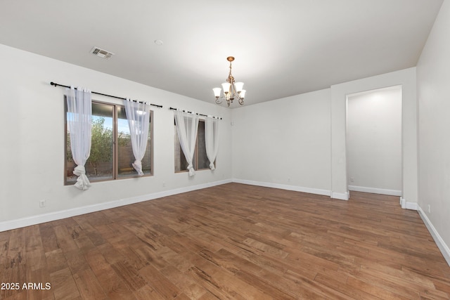 unfurnished room with wood-type flooring and a chandelier