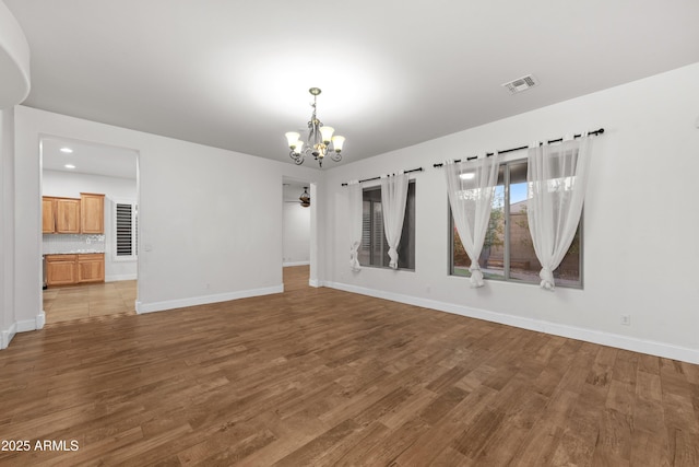 unfurnished room with hardwood / wood-style flooring and ceiling fan with notable chandelier