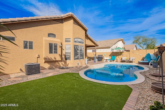 view of pool with a patio area, a yard, cooling unit, and a fenced backyard