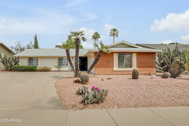 single story home with driveway, brick siding, and an attached garage