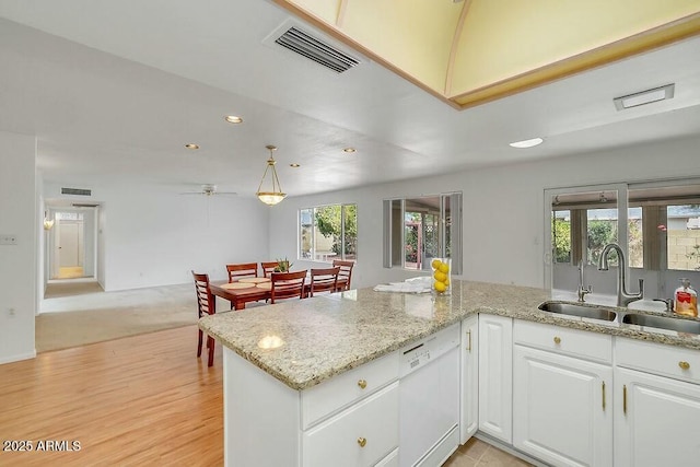 kitchen featuring a sink, visible vents, dishwasher, white cabinets, and light stone countertops