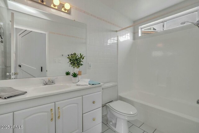 full bath with tile patterned floors, toilet, vanity, shower / tub combination, and tile walls