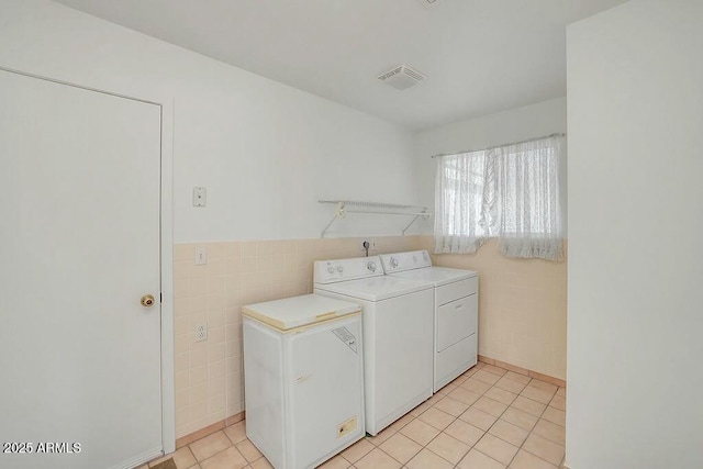 laundry room with tile walls, visible vents, independent washer and dryer, and laundry area