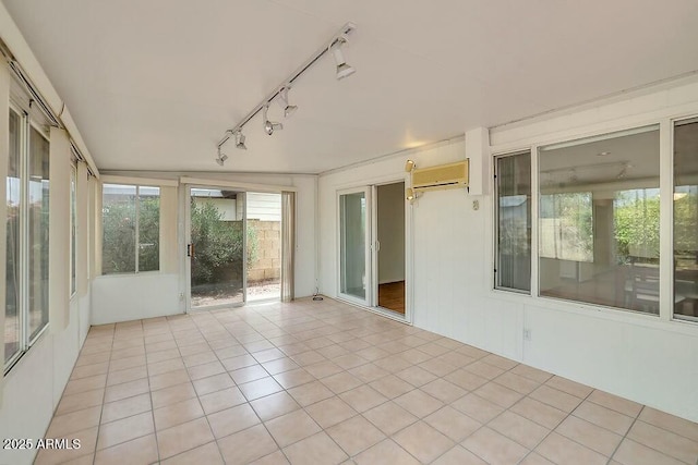 unfurnished sunroom featuring tile patterned flooring, an AC wall unit, and rail lighting