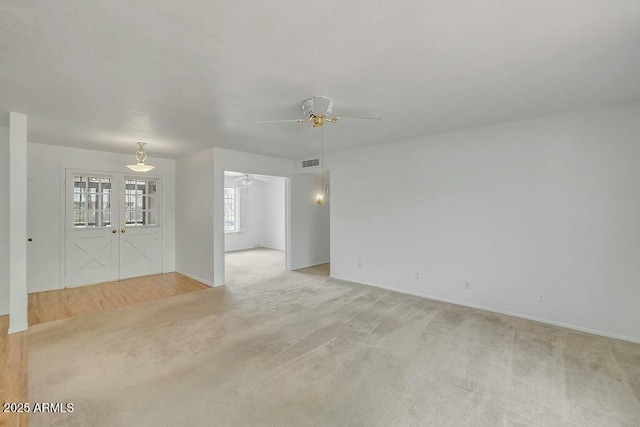 empty room featuring light colored carpet, visible vents, ceiling fan, and french doors