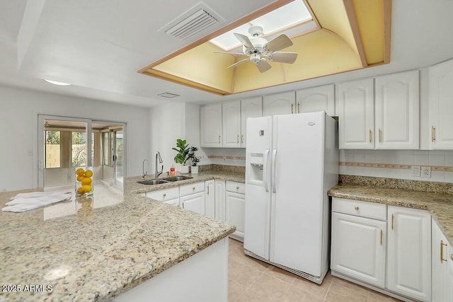 kitchen with white refrigerator with ice dispenser, visible vents, white cabinets, and a sink