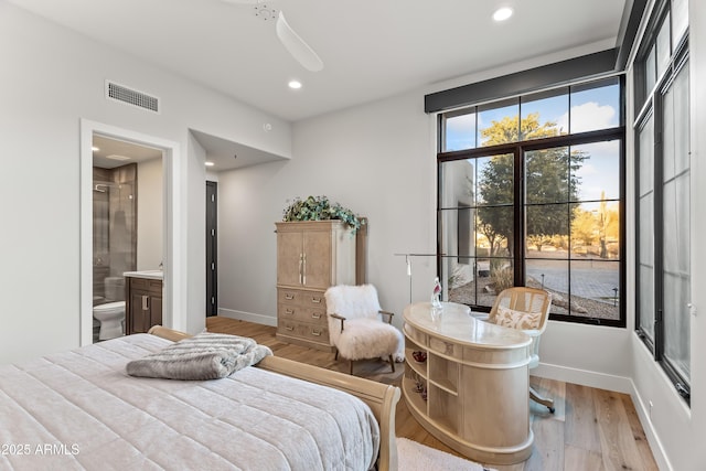 bedroom with connected bathroom and light hardwood / wood-style flooring