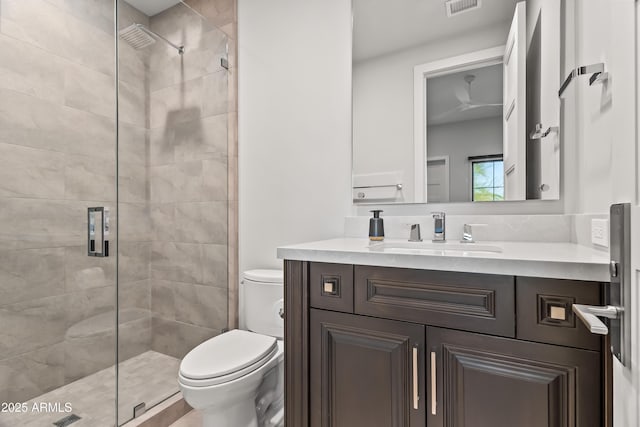 bathroom featuring vanity, toilet, and a tile shower