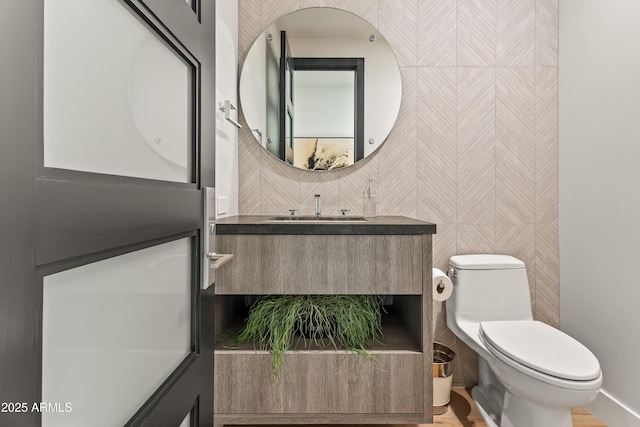 bathroom with vanity, tile walls, and toilet