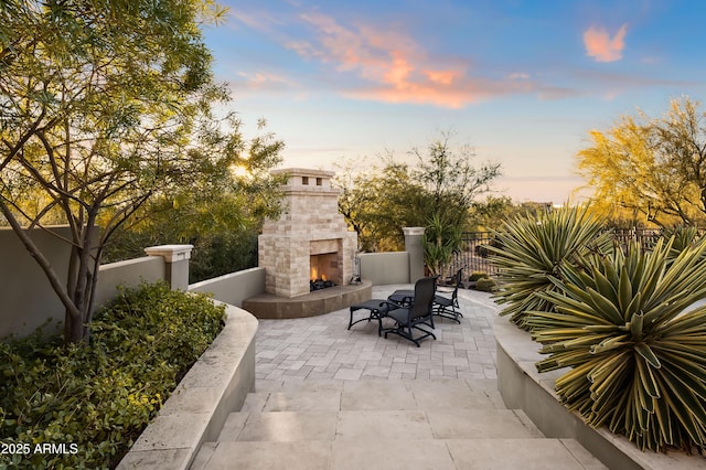 patio terrace at dusk featuring exterior fireplace