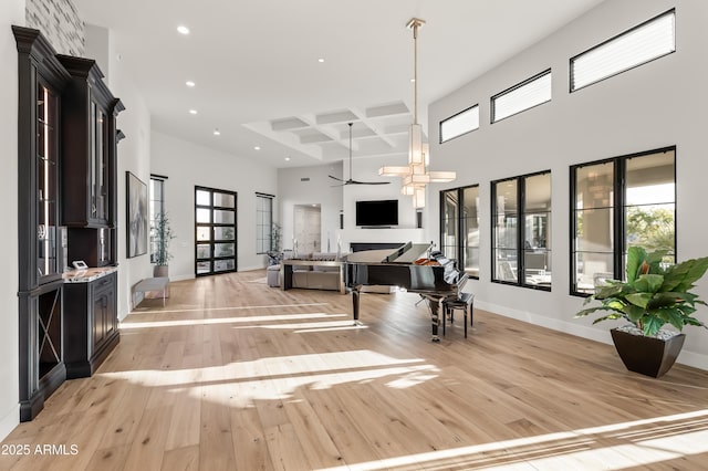 interior space featuring coffered ceiling, a wealth of natural light, light hardwood / wood-style floors, and a high ceiling