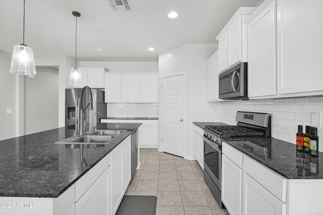 kitchen with stainless steel appliances, sink, pendant lighting, white cabinets, and an island with sink