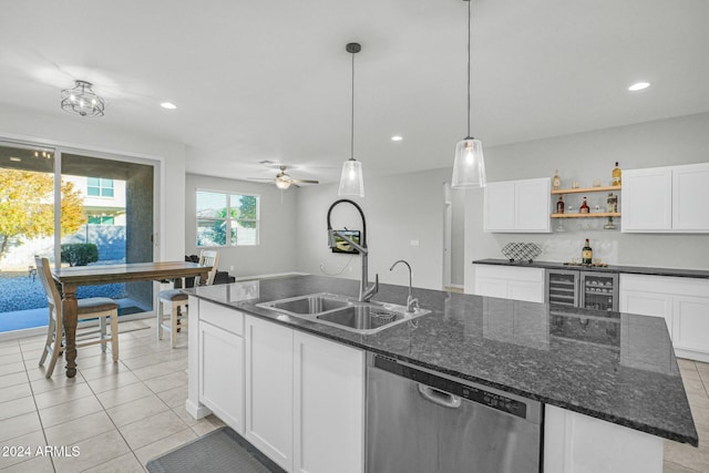 kitchen with a center island with sink, stainless steel dishwasher, ceiling fan, dark stone countertops, and decorative light fixtures