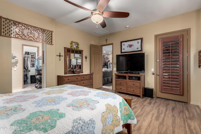 20962 W Thomas Rd, Buckeye, AZ 85396 - bedroom featuring light wood-type flooring, a walk in closet, a closet, ceiling fan, and baseboards