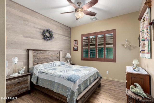20962 W Thomas Rd, Buckeye, AZ 85396 - bedroom with wooden walls, wood finished floors, baseboards, a ceiling fan, and an accent wall