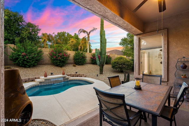 pool at dusk with a patio, outdoor dining area, a fenced backyard, and a fenced in pool