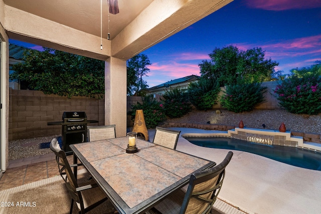 patio terrace at dusk featuring a fenced backyard, outdoor dining area, area for grilling, and a fenced in pool