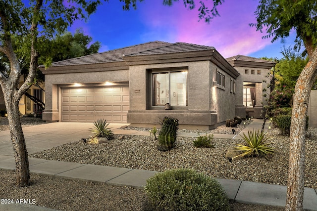 view of front facade with stucco siding, an attached garage, a tile roof, and concrete driveway