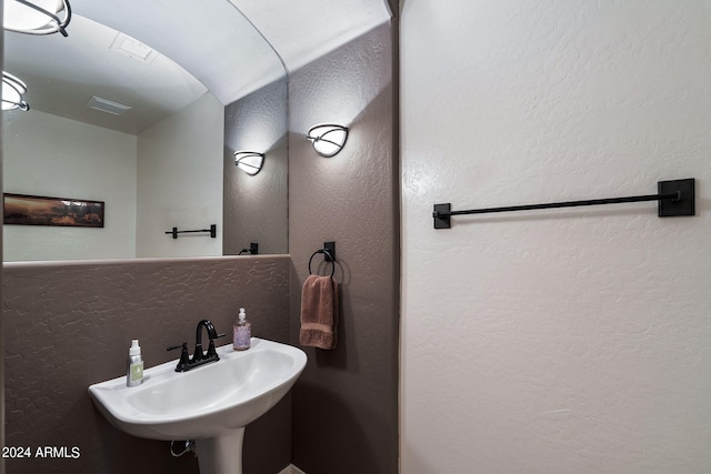 bathroom featuring a textured wall, visible vents, and a sink