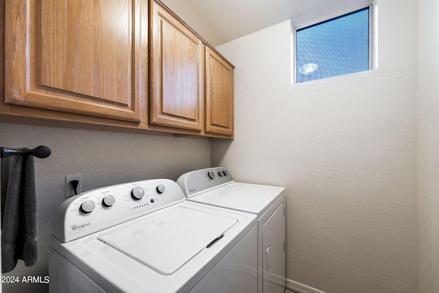 laundry room with independent washer and dryer, cabinet space, and a textured wall