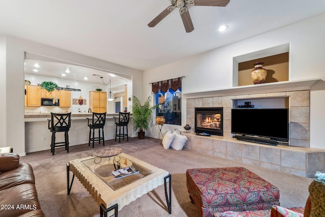 carpeted living area featuring baseboards, recessed lighting, a tiled fireplace, and a ceiling fan